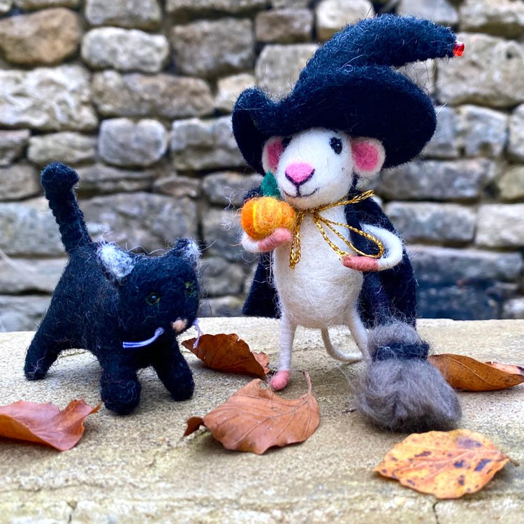 A hand-felted organic wool toy set featuring a Halloween Witch Mouse and a Black Cat, both wearing costumes and accessories, displayed with autumn leaves on a stone surface.