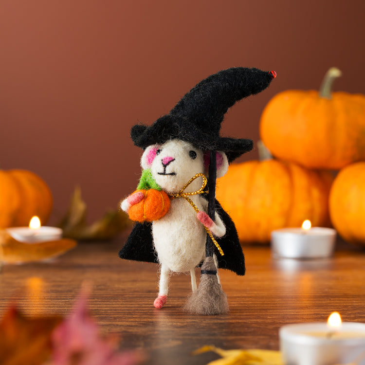 Halloween witch mouse ornament with pumpkins and candles on a wooden table